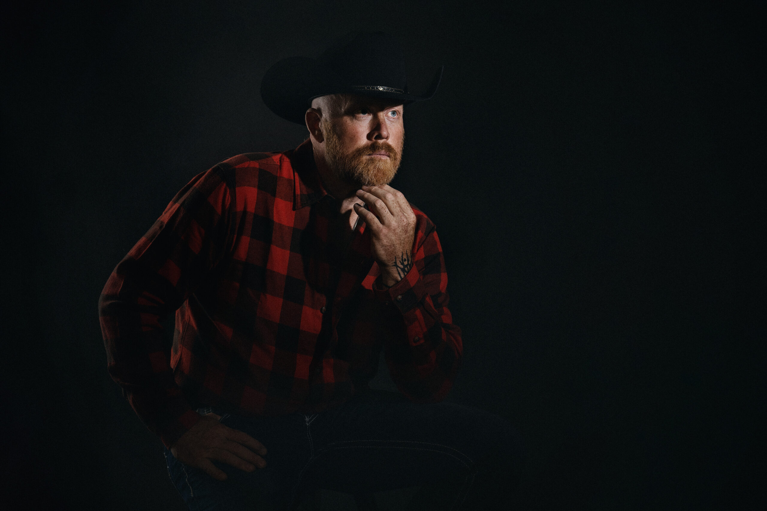 Cinematic chiaroscuro portrait of a man in a cowboy hat, photographed at a fine art portrait studio in Kirkland serving Seattle and Bellevue